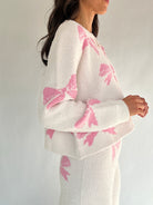 White outfit with pink bow patterns on a plain background side of top