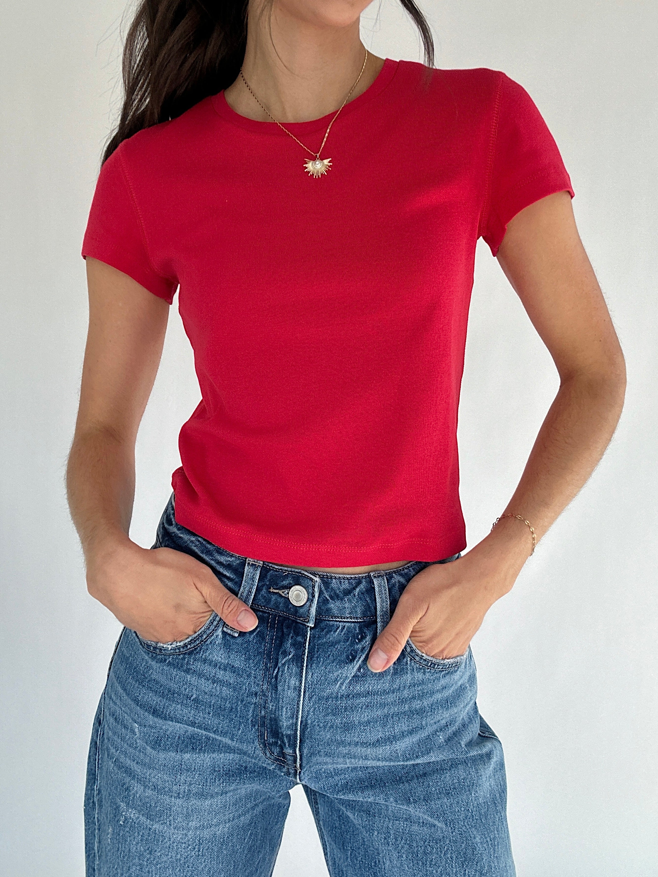 Person wearing a red t-shirt and blue jeans against a plain background