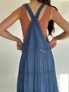 Person wearing a blue overall dress with lace details showing the classic overall style back