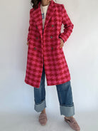 Light and dark pink houndstooth coat with button front paired with denim jeans on a white background