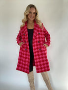 Woman with hands in pockets of red and pink houndstooth tweed coat