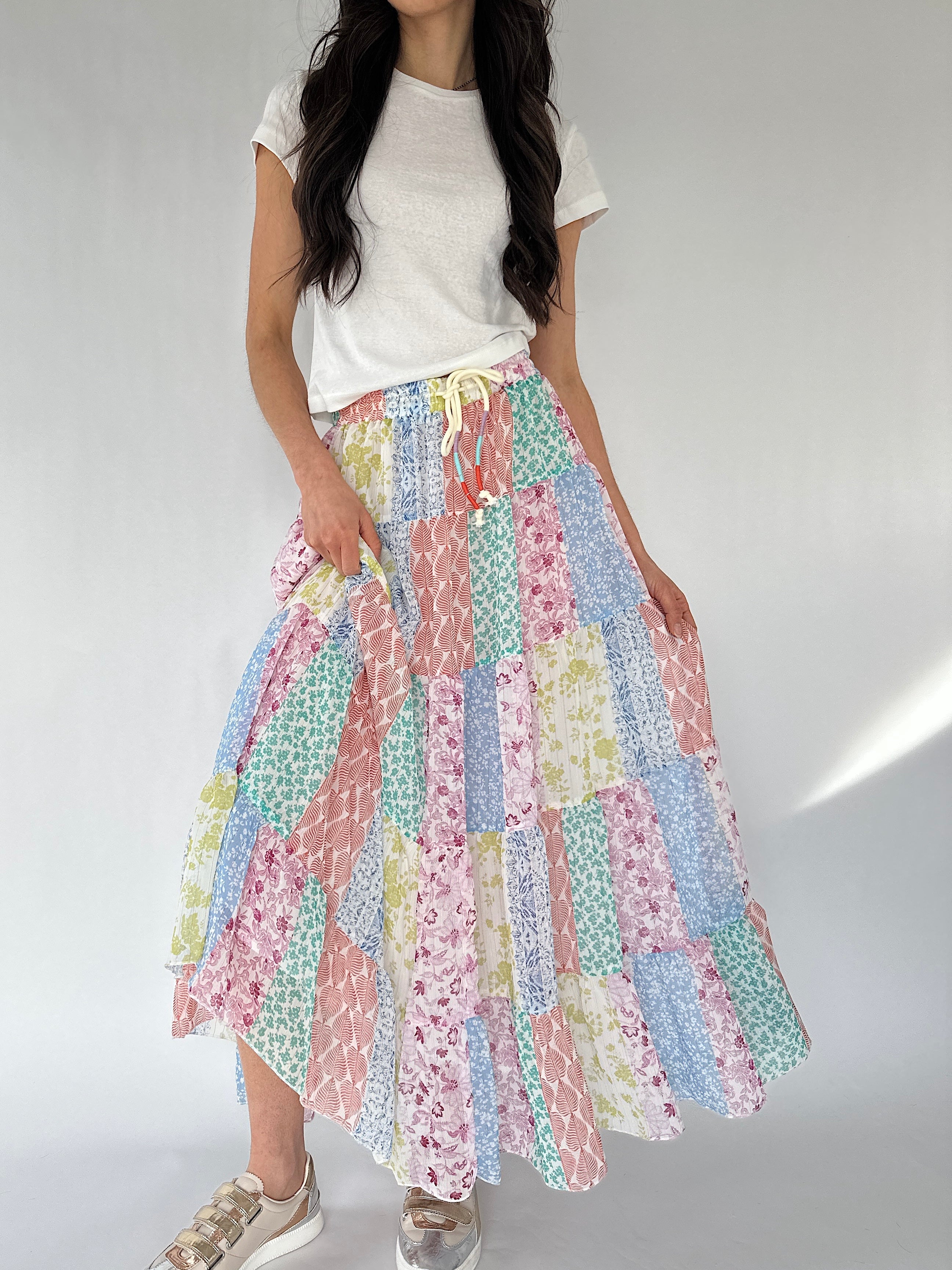 Woman wearing a colorful patchwork skirt on a plain background