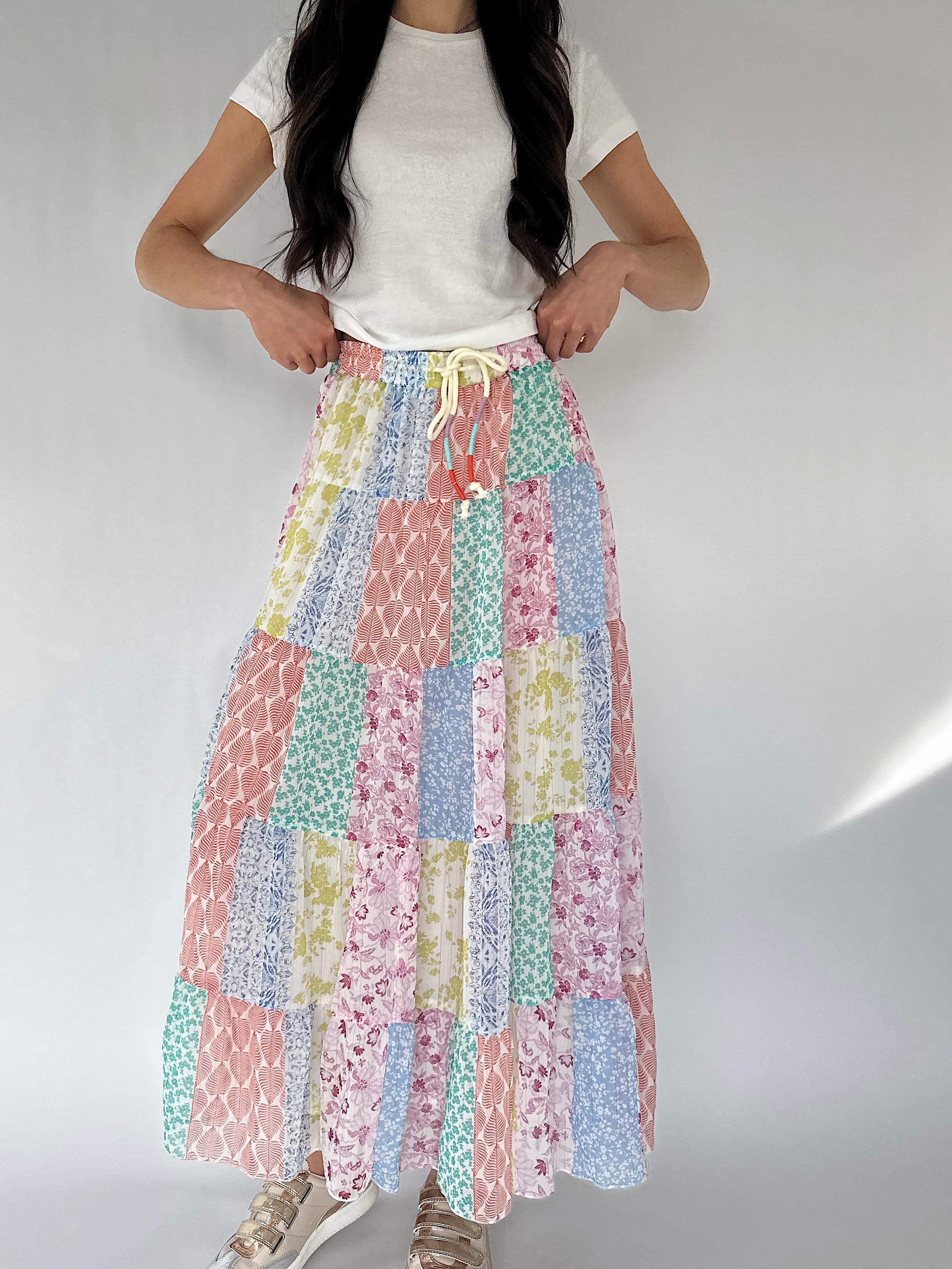 Person wearing a colorful patchwork skirt on a plain background