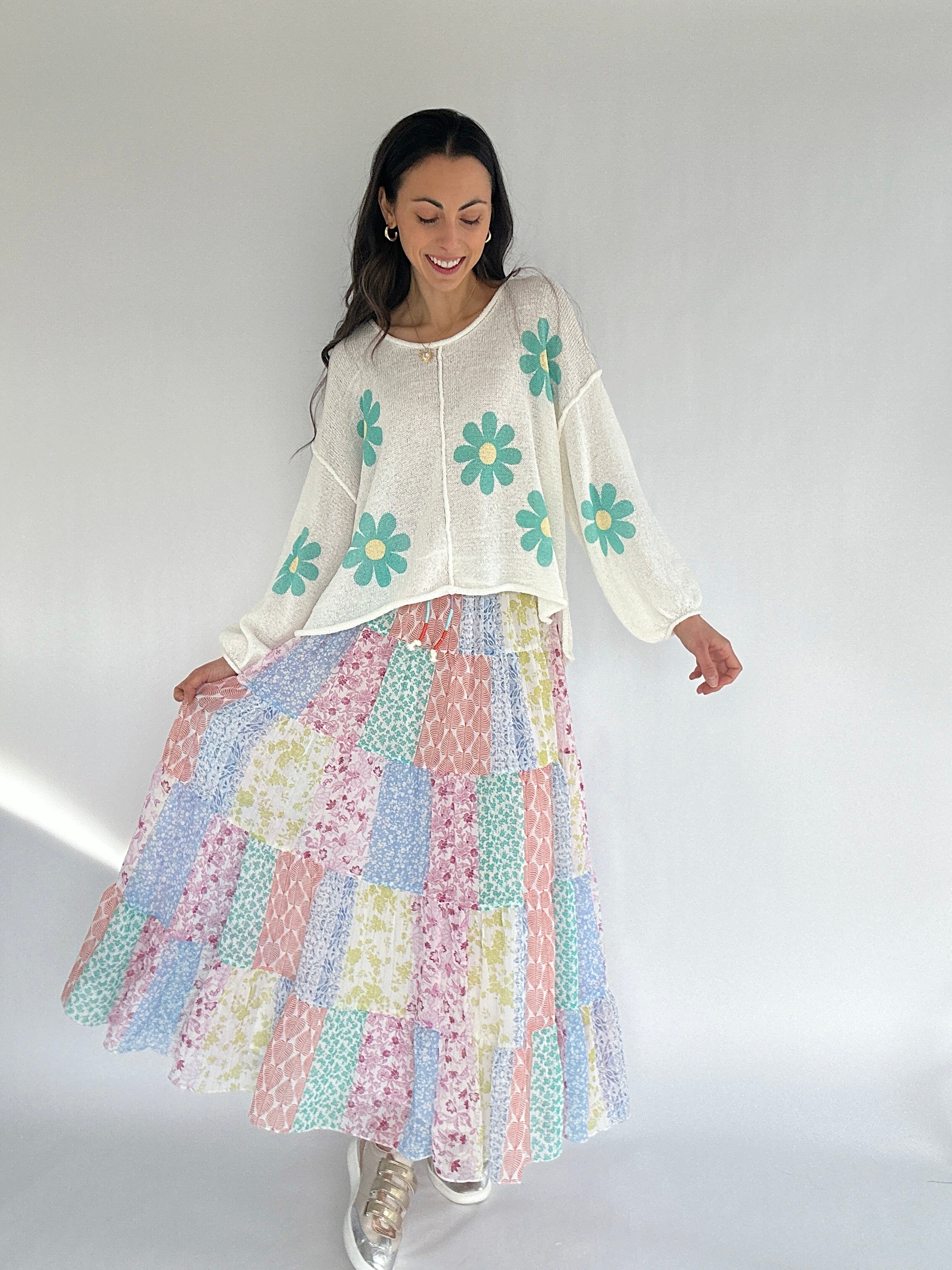 Woman wearing a floral dress and daisy sweater with a white background