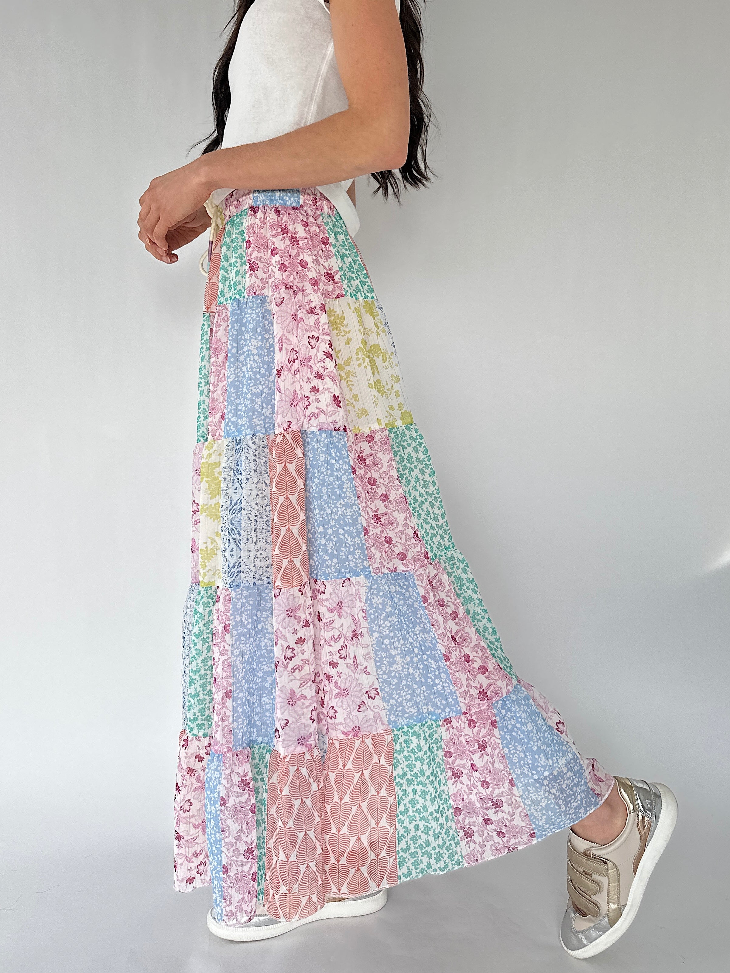 Person wearing a colorful patchwork skirt on a plain background from side