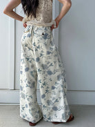 Person wearing a beige crochet top and floral wide-leg pants showing the back pocket details against a white background