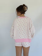 Person wearing a pink and white floral pajama set against a plain background in back