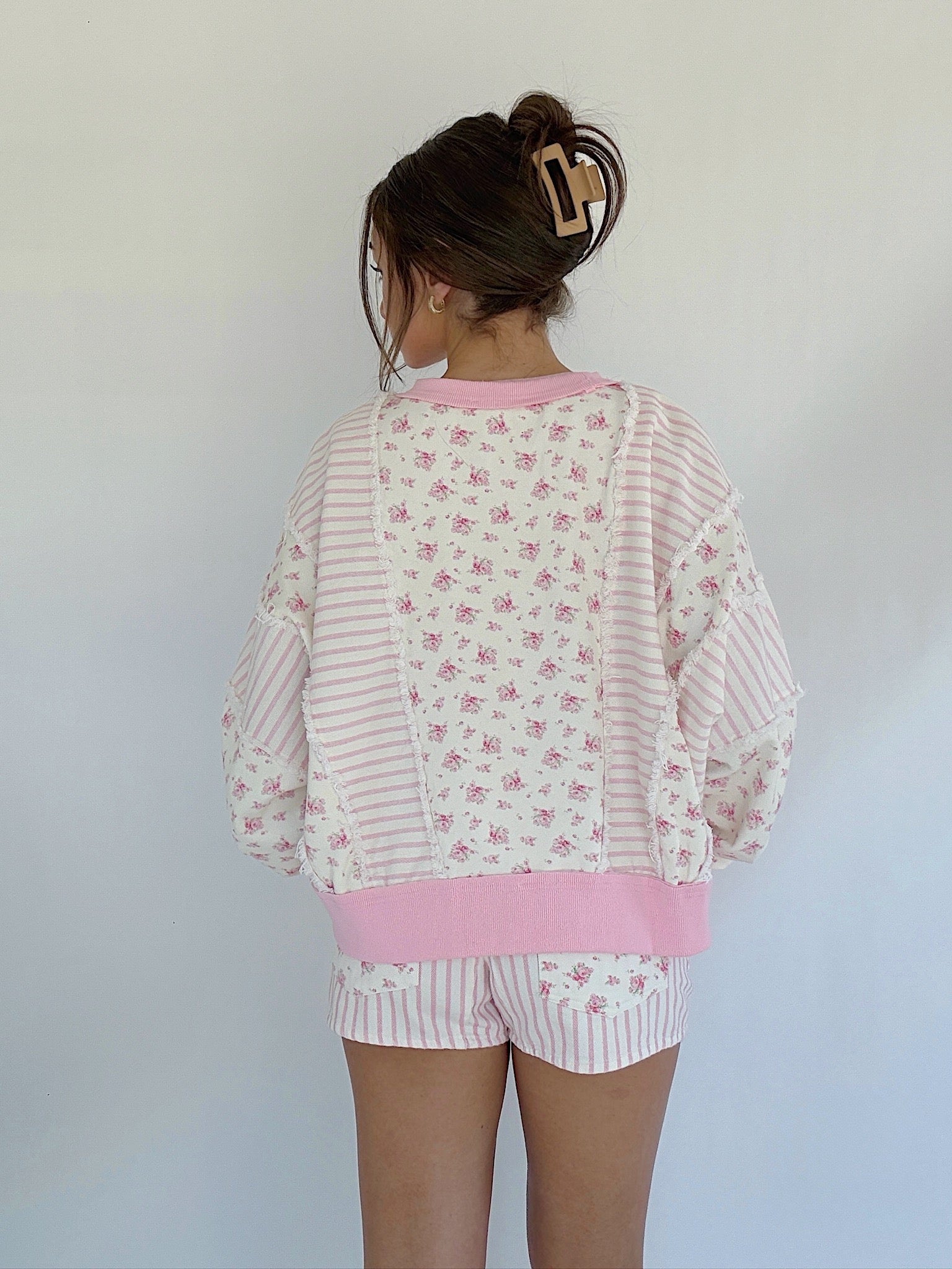 Person wearing a pink and white floral pajama set against a plain background in back