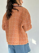 Person wearing an orange plaid jacket against a white background
