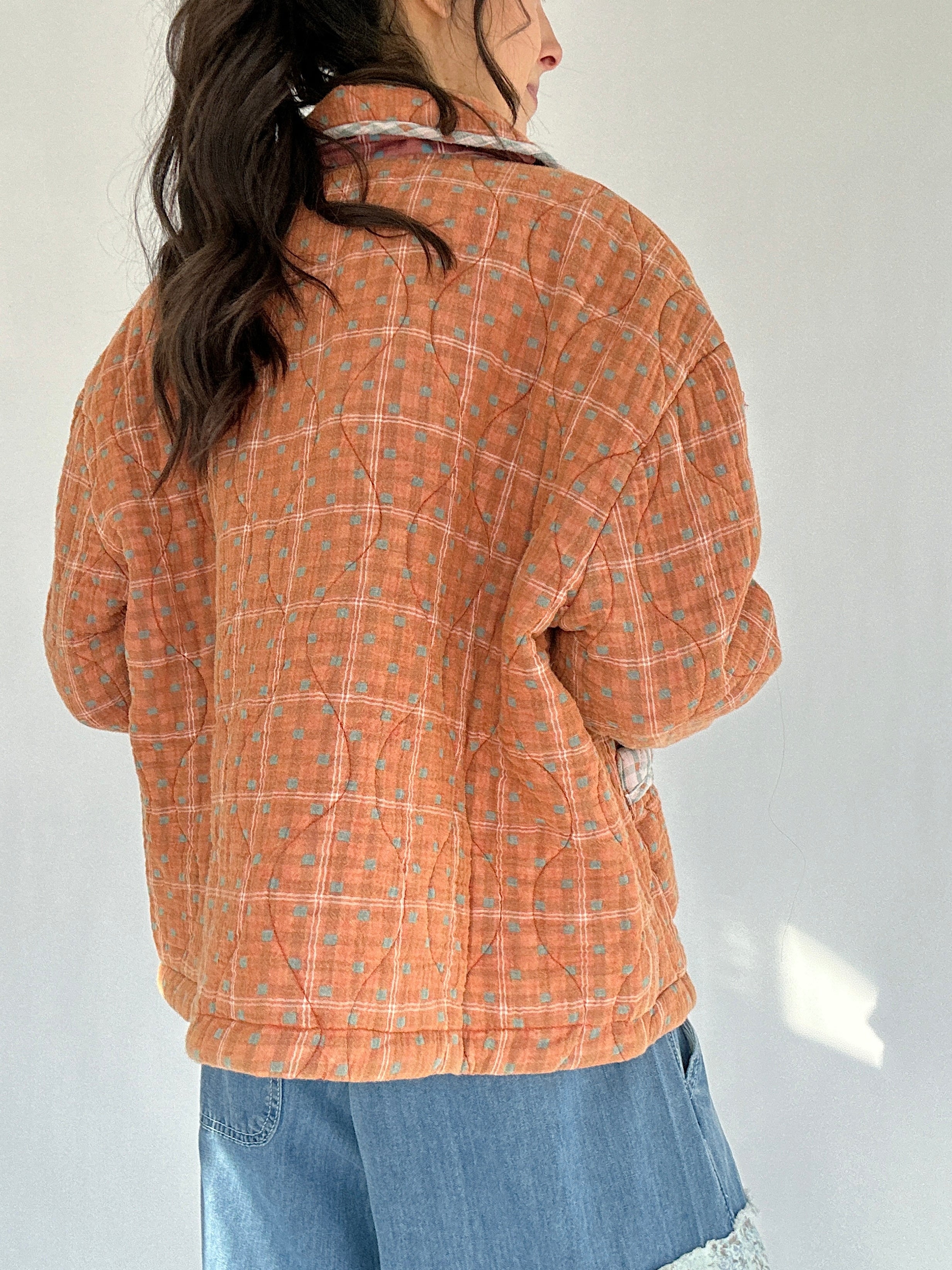 Person wearing an orange plaid jacket against a white background