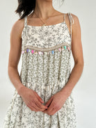 Woman wearing a floral dress with decorative straps against a white background