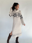 Woman wearing a long, patterned sweater dress against a plain background
