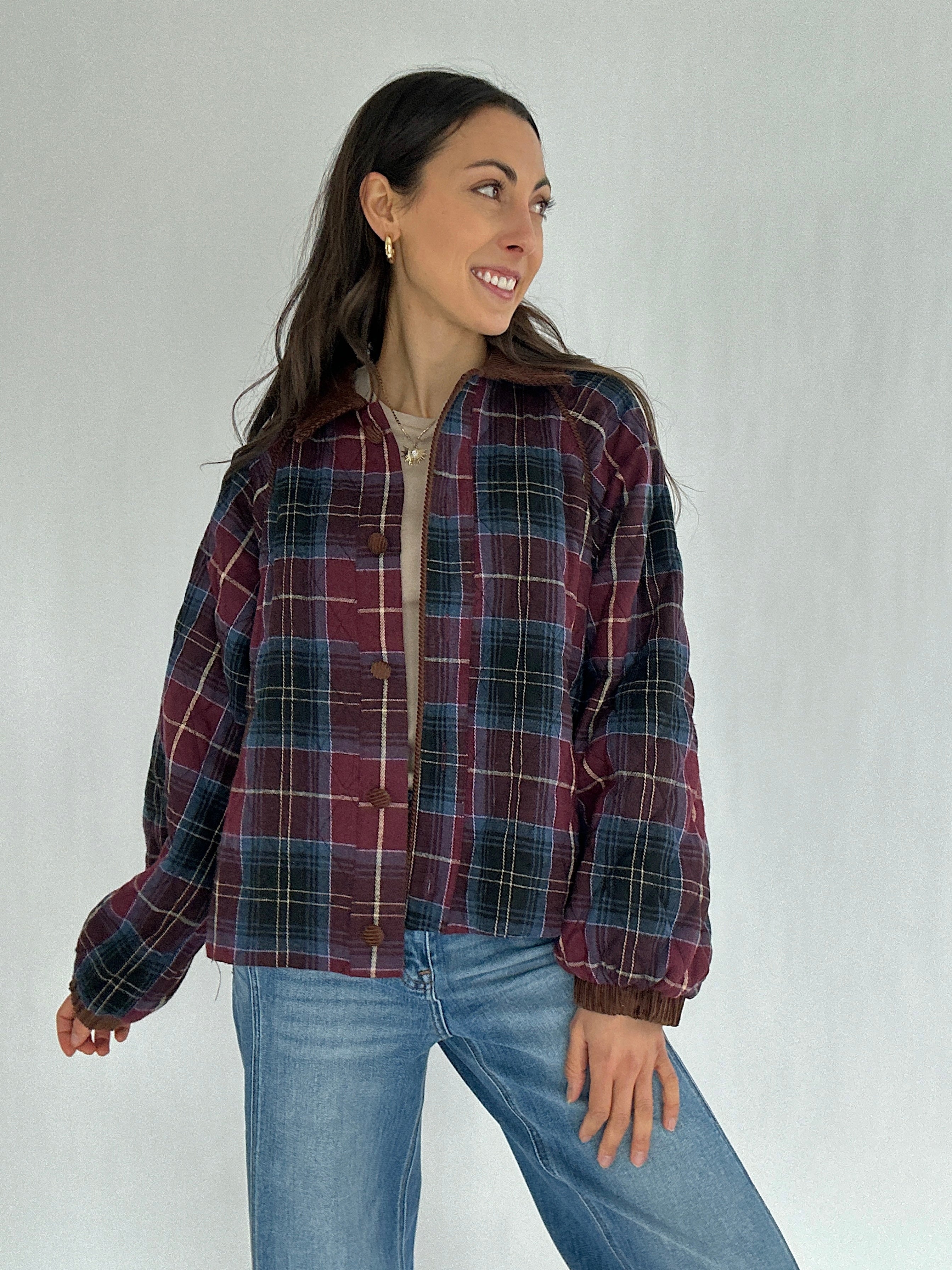 Woman wearing a maroon plaid jacket and jeans against a plain background