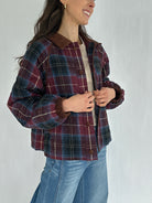 Person wearing a maroon plaid jacket with a plain background