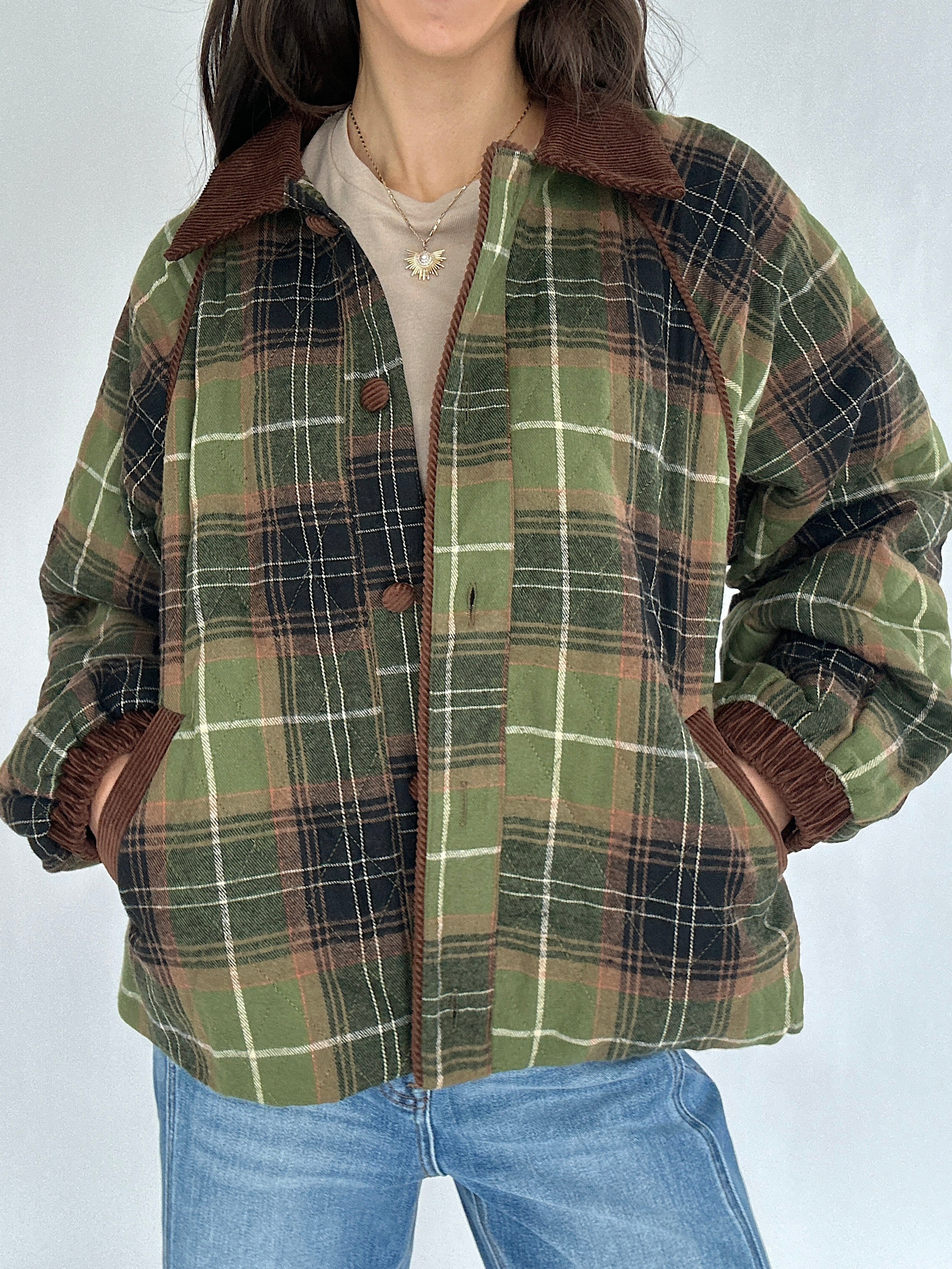 Person wearing a green plaid jacket with brown trim on a white background