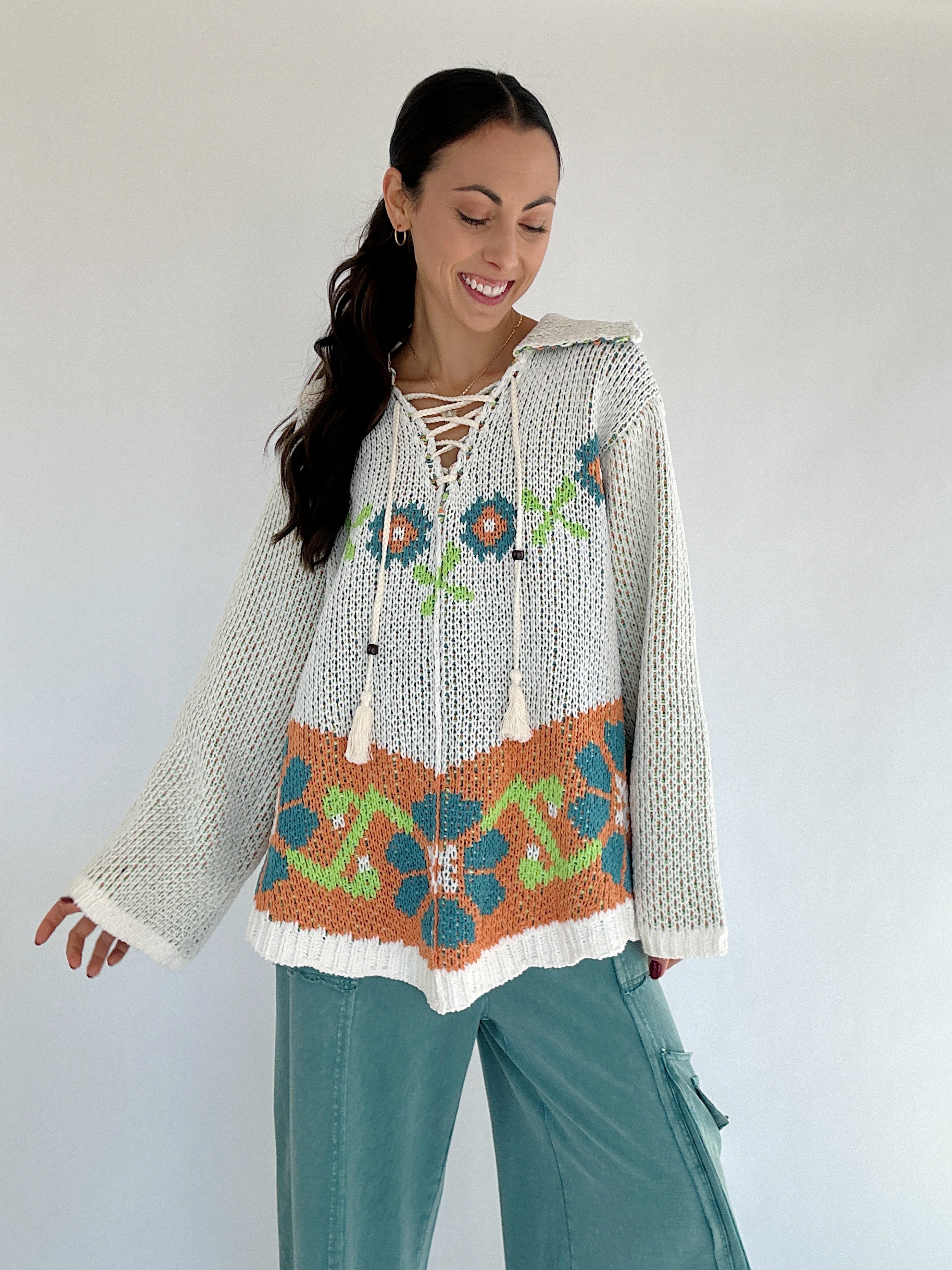 Woman wearing a patterned chenille sweater top with a white background