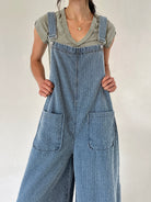 Person wearing blue denim textured overalls over a green t-shirt against a plain background