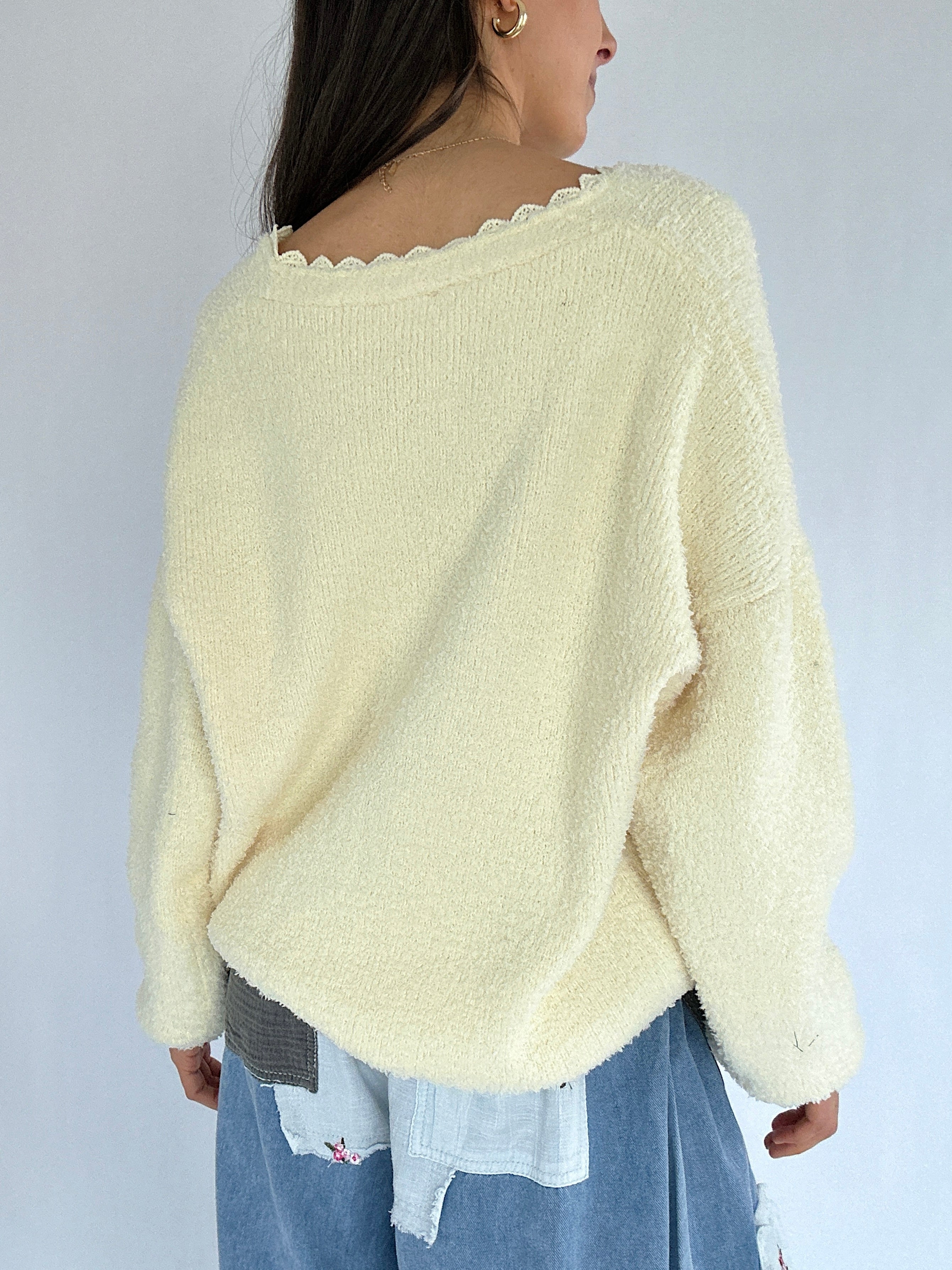 Person wearing a light yellow sweater with a plain background showing the back