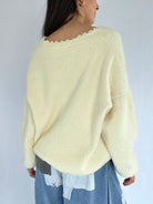 Person wearing a light yellow sweater with a plain background showing the back