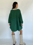 Person wearing a green dress with long sleeves and a white background back view