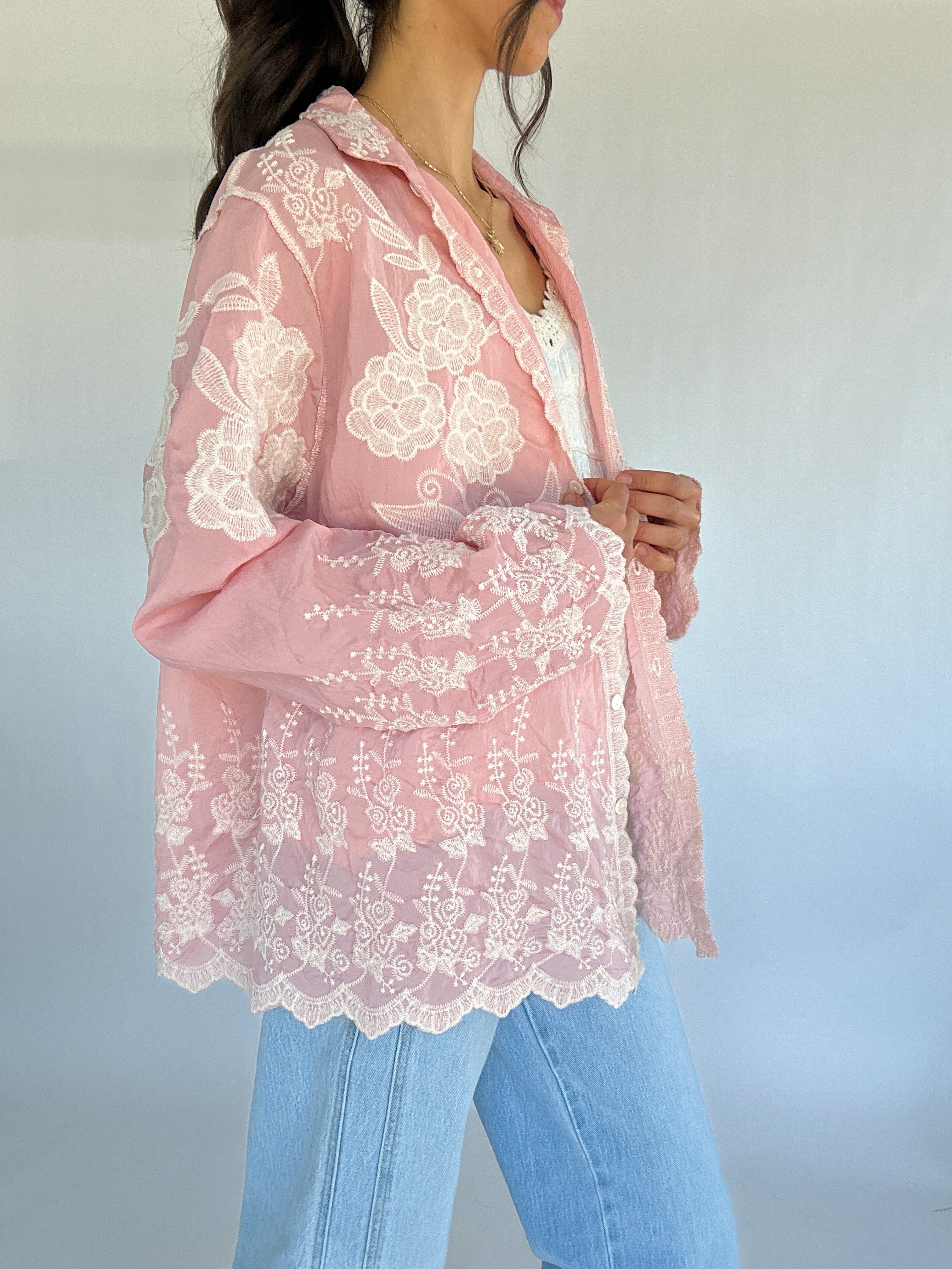 Pink lace blouse worn by a person with a blurred background showing side