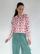 Woman wearing a candy cane and bow printed cardigan and teal pants on a white background