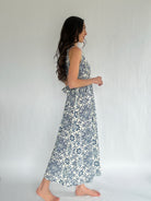 Woman wearing a floral dress against a plain background from side