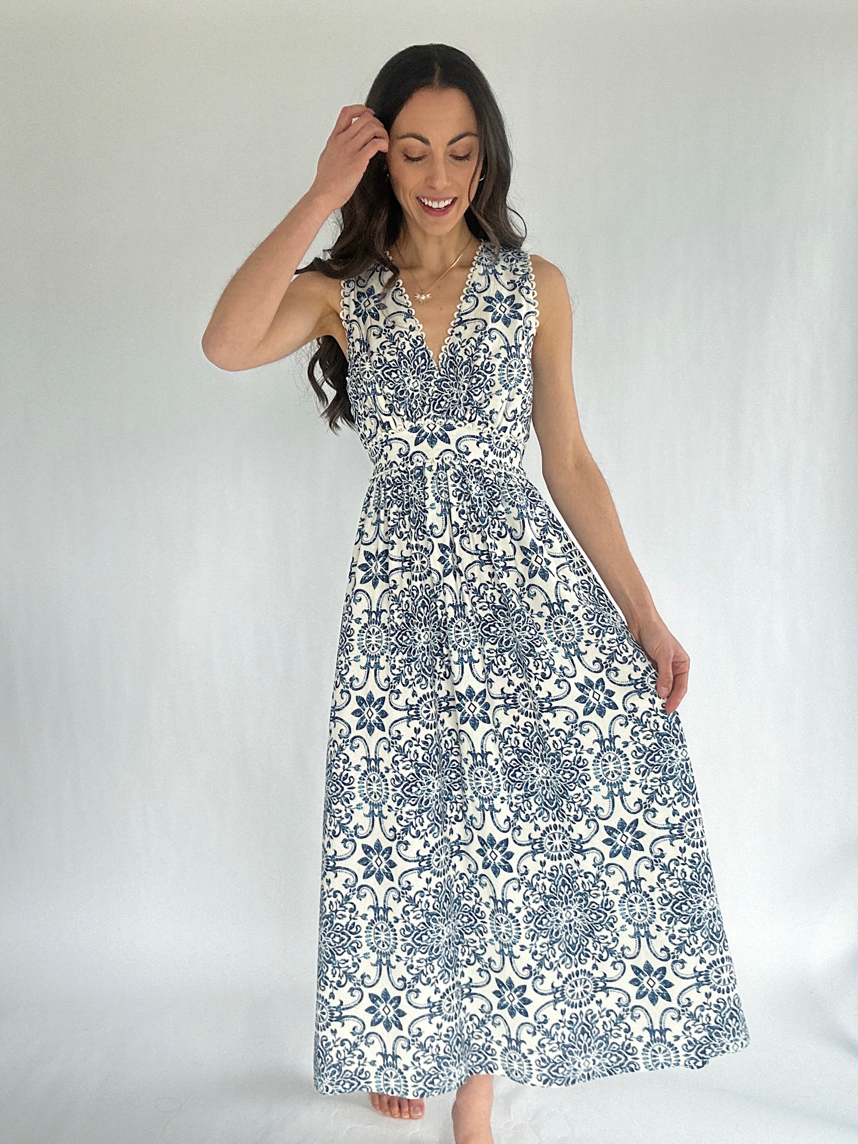 Woman wearing a sleeveless dress with a blue and white pattern on a plain background
