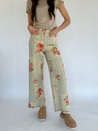 Person wearing floral and checkered patterned pants on a white background