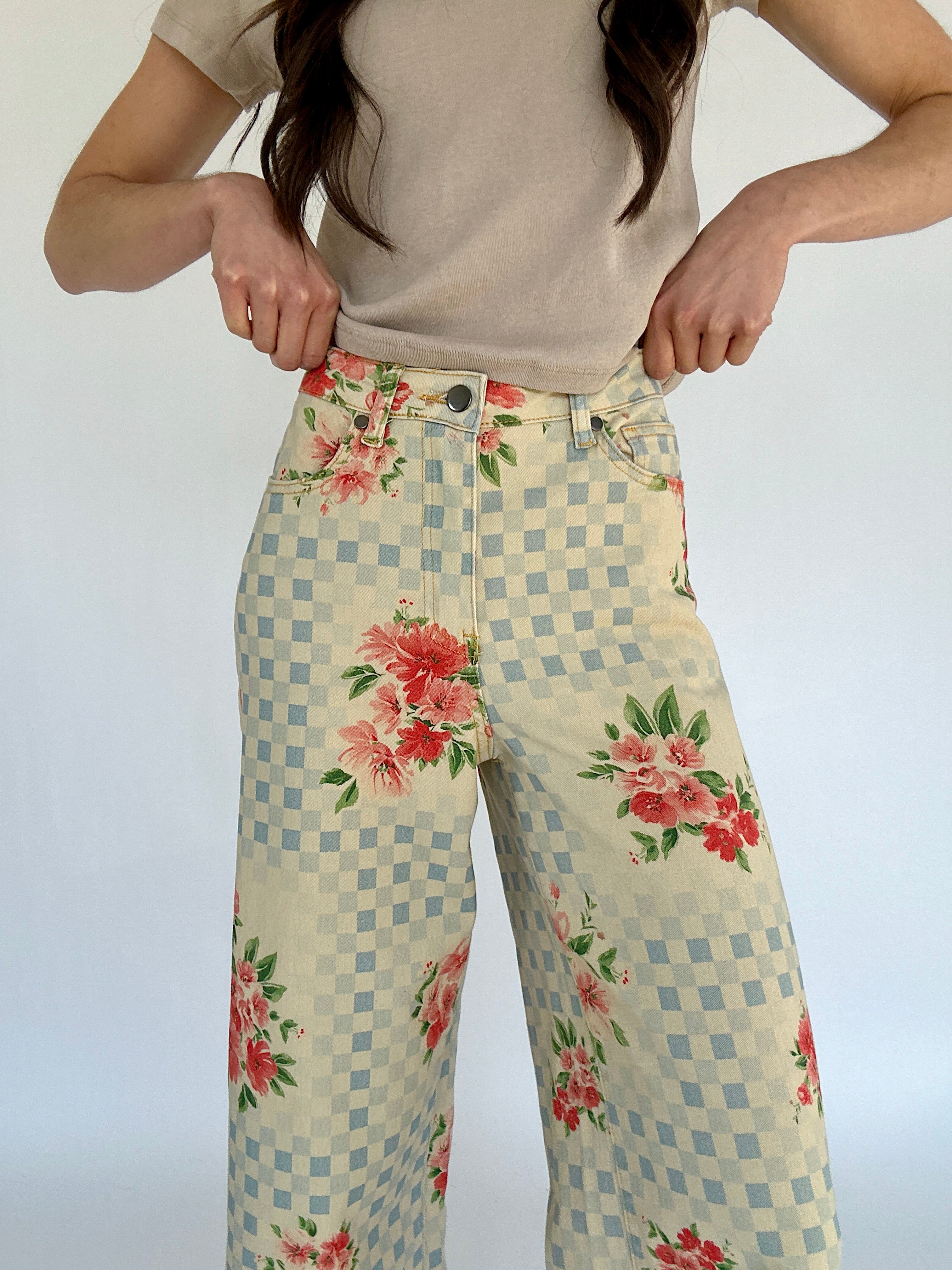 Person wearing floral checkered pants with a plain background showing button and zip fly