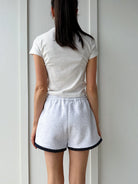 Person wearing a white t-shirt and shorts against a plain background from back