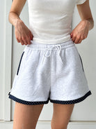 Person wearing gray shorts with navy polka dot trim on a white background
