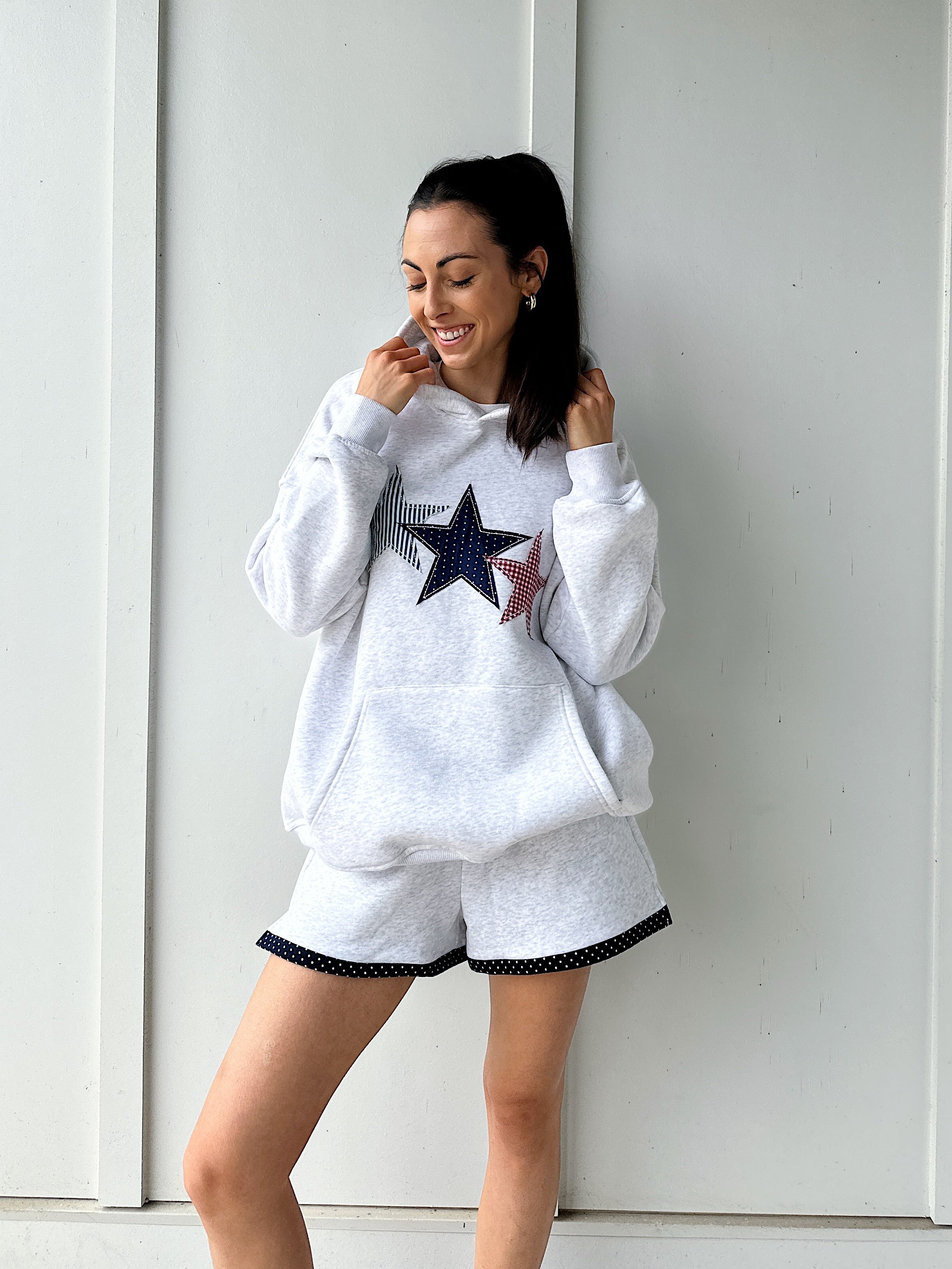 Woman wearing a grey sweatshirt with a star design and matching shorts against a white background
