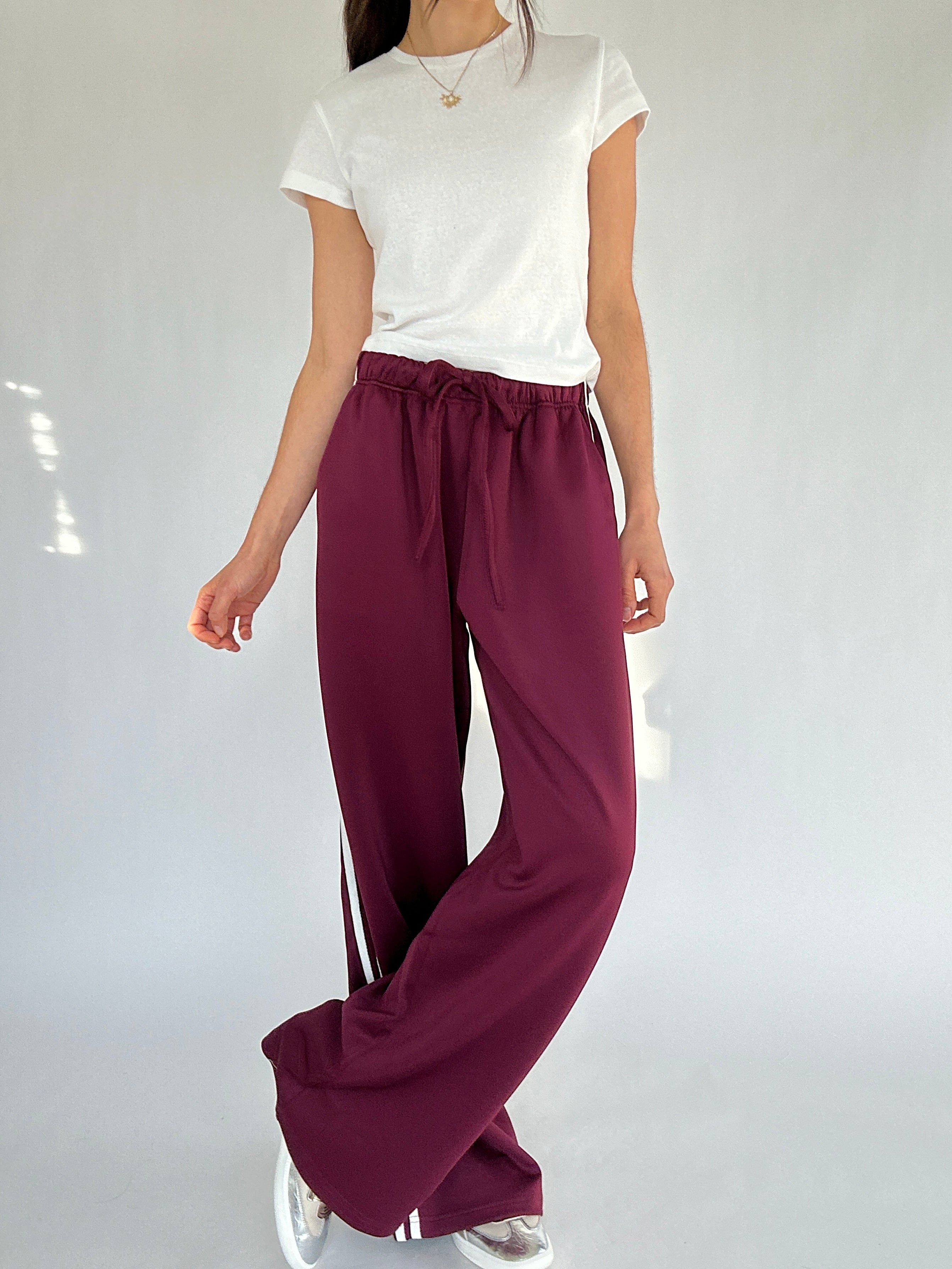 Person wearing a white top and burgundy wide-leg pants on a plain background