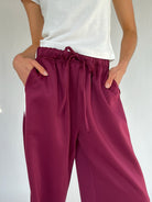 Maroon pants with a drawstring waist worn by a person on a white background