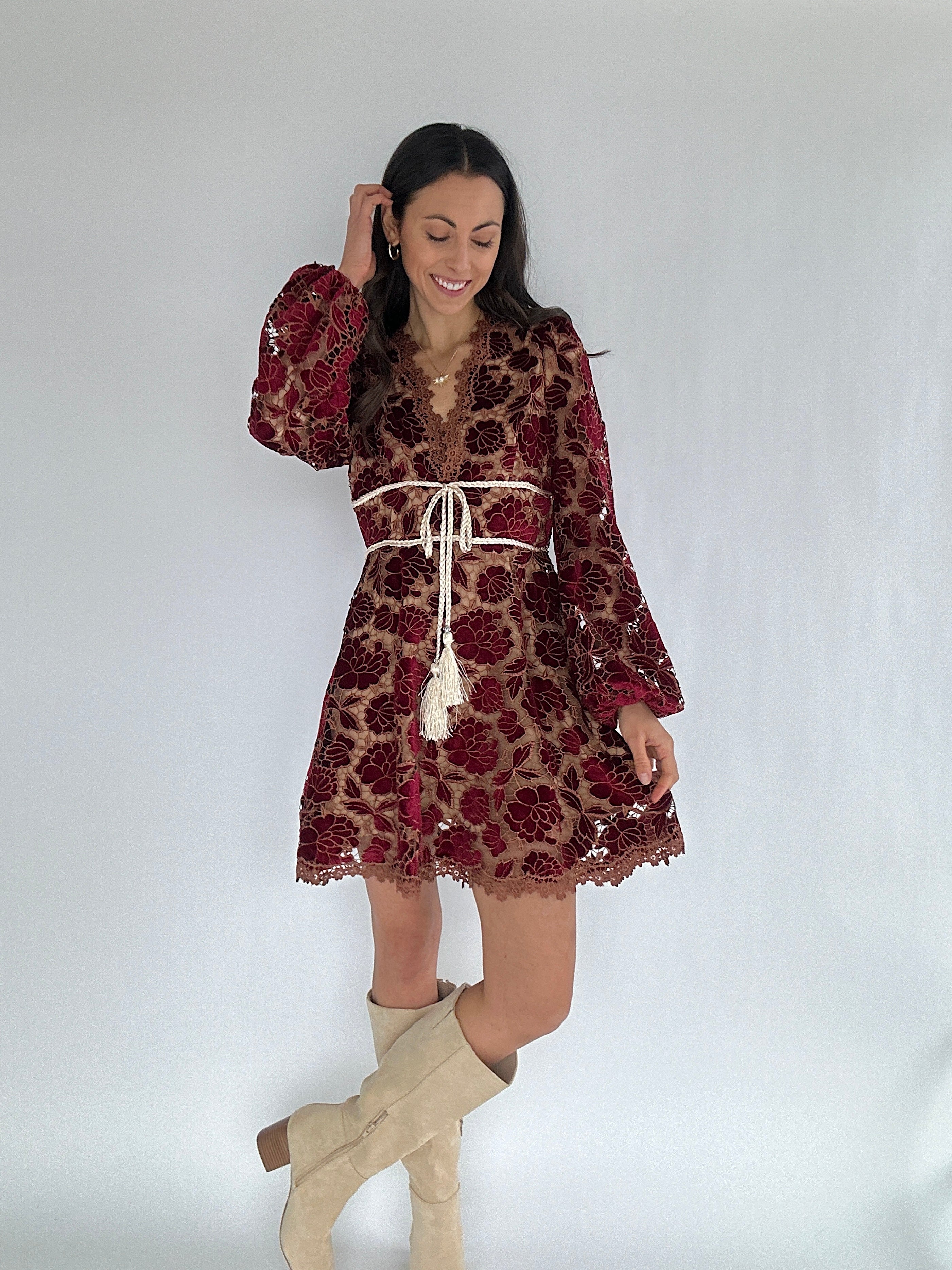 Woman wearing a red velvet burnout mini dress with long sleeves and a white background