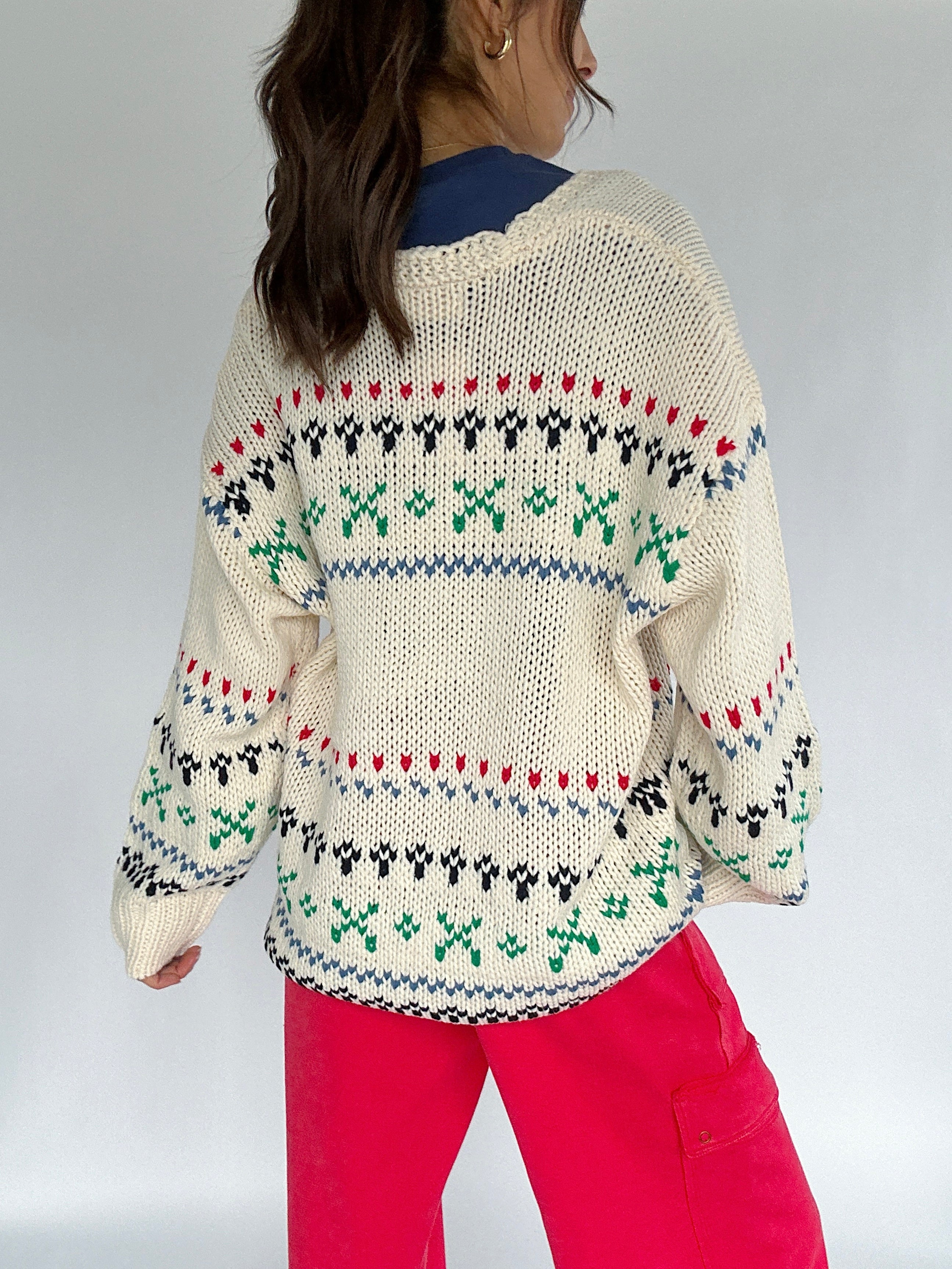 Person wearing a patterned sweater with a plain background back view