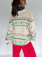 Person wearing a patterned sweater with a plain background back view