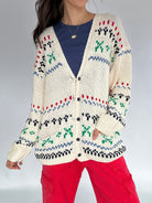 Person wearing a patterned cardigan with a plain background