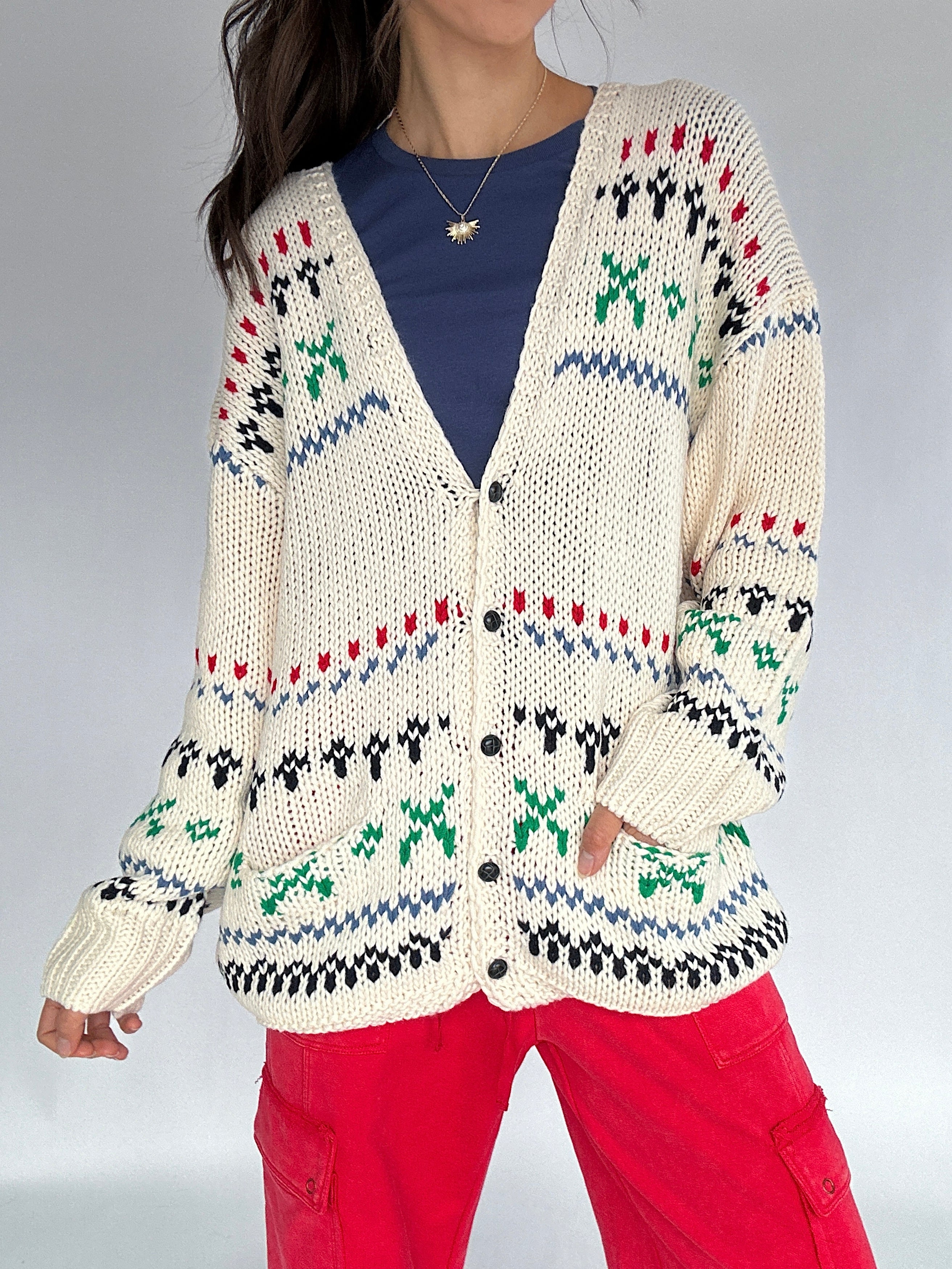 Person wearing a patterned cardigan with a plain background