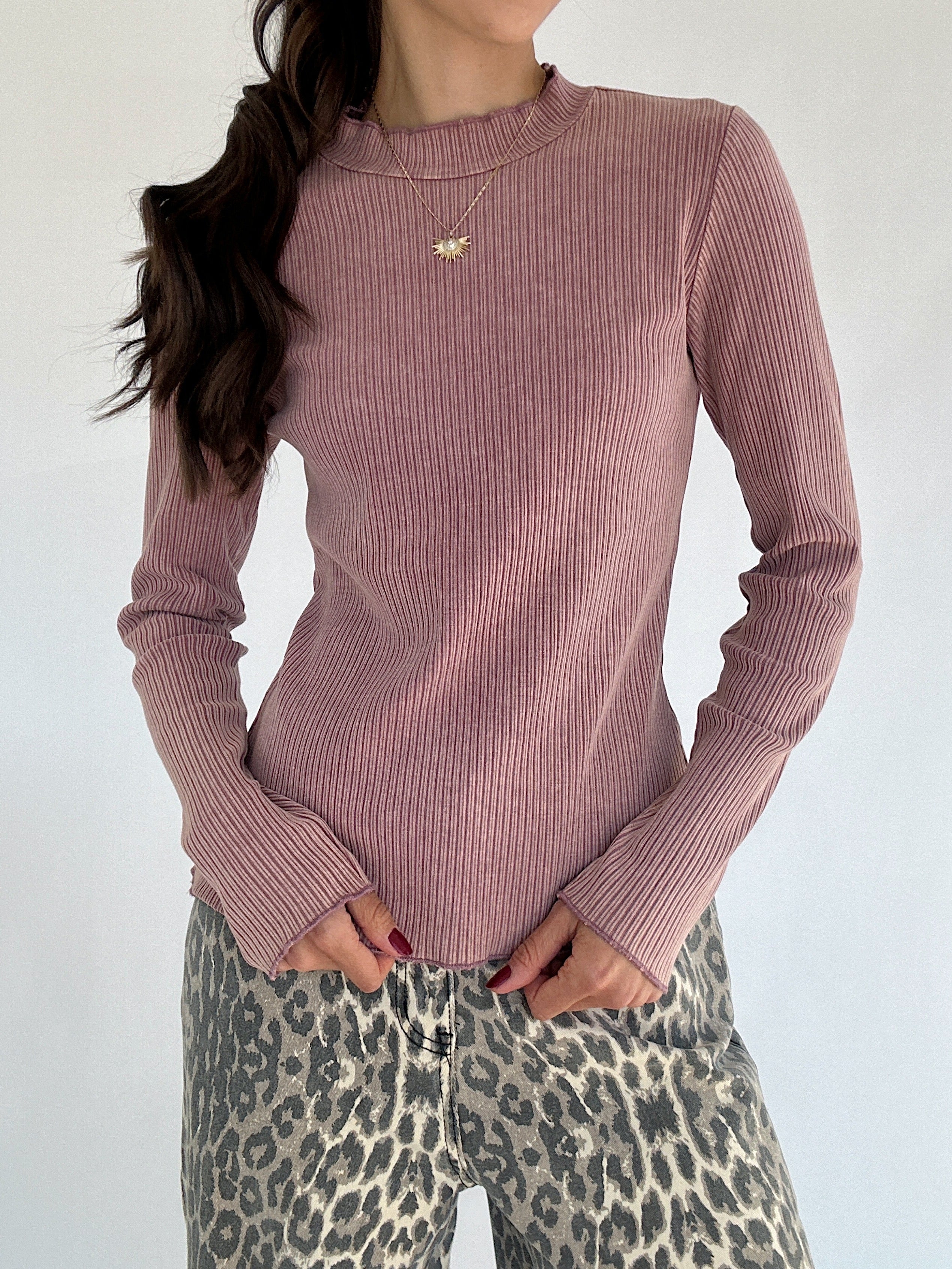 Person wearing a ribbed pink long sleeve and leopard print pants against a plain background