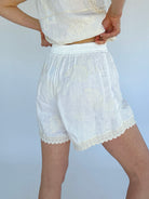 White lace shorts worn by a person on a plain background