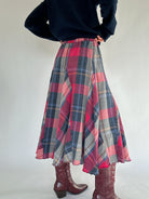 Person wearing a plaid skirt and dark sweater on a plain background from back