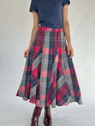 Person wearing a plaid maxi skirt and blue tee with a plain background