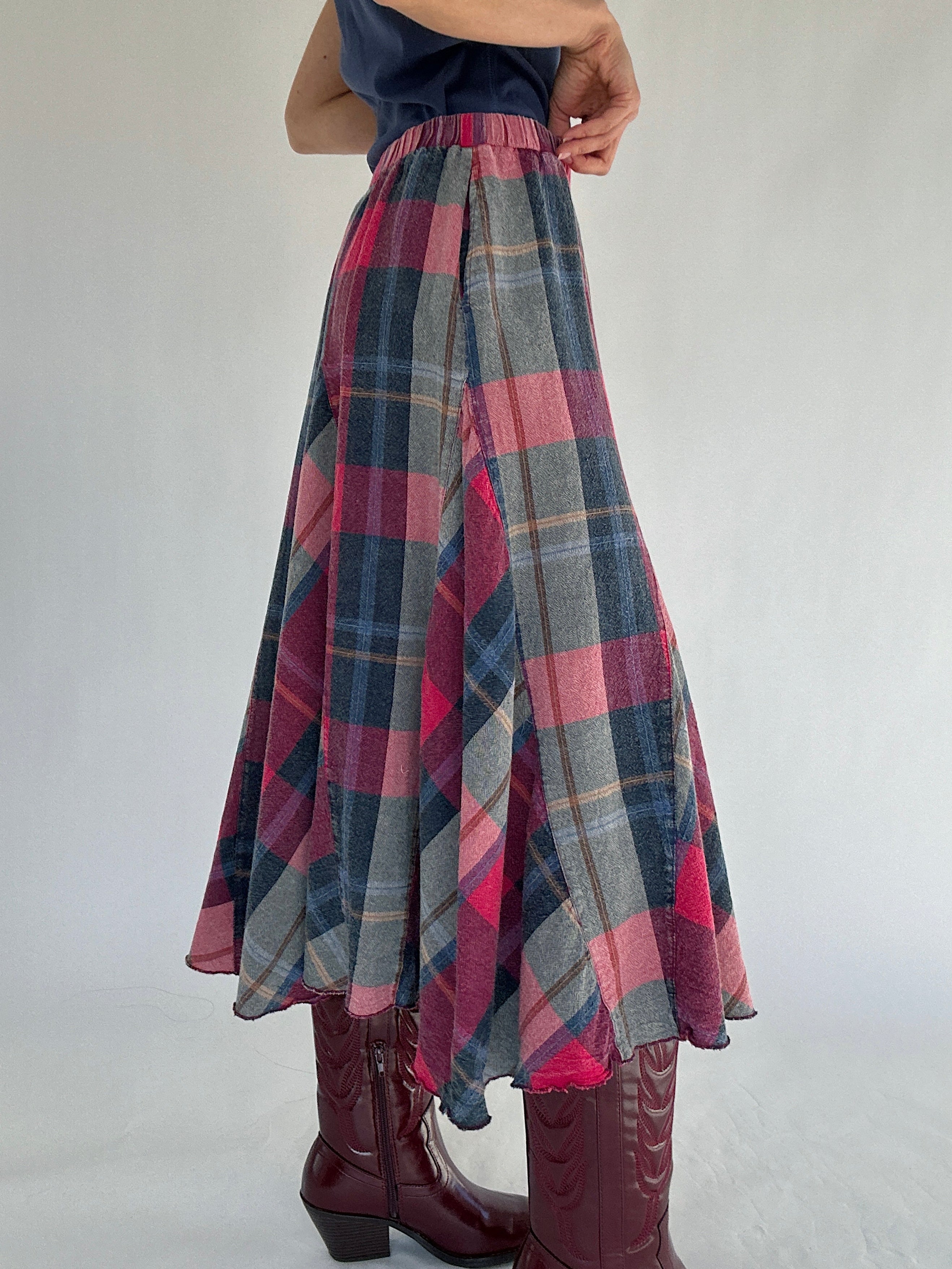 Person wearing a blue and red plaid maxi skirt from side on a white background