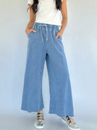 Person wearing light blue wide-leg sweatpants with a white top on a plain background