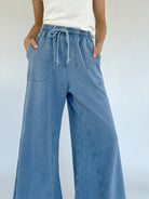 Person wearing blue wide-leg pants with a white background showing drawstring waist and pockets