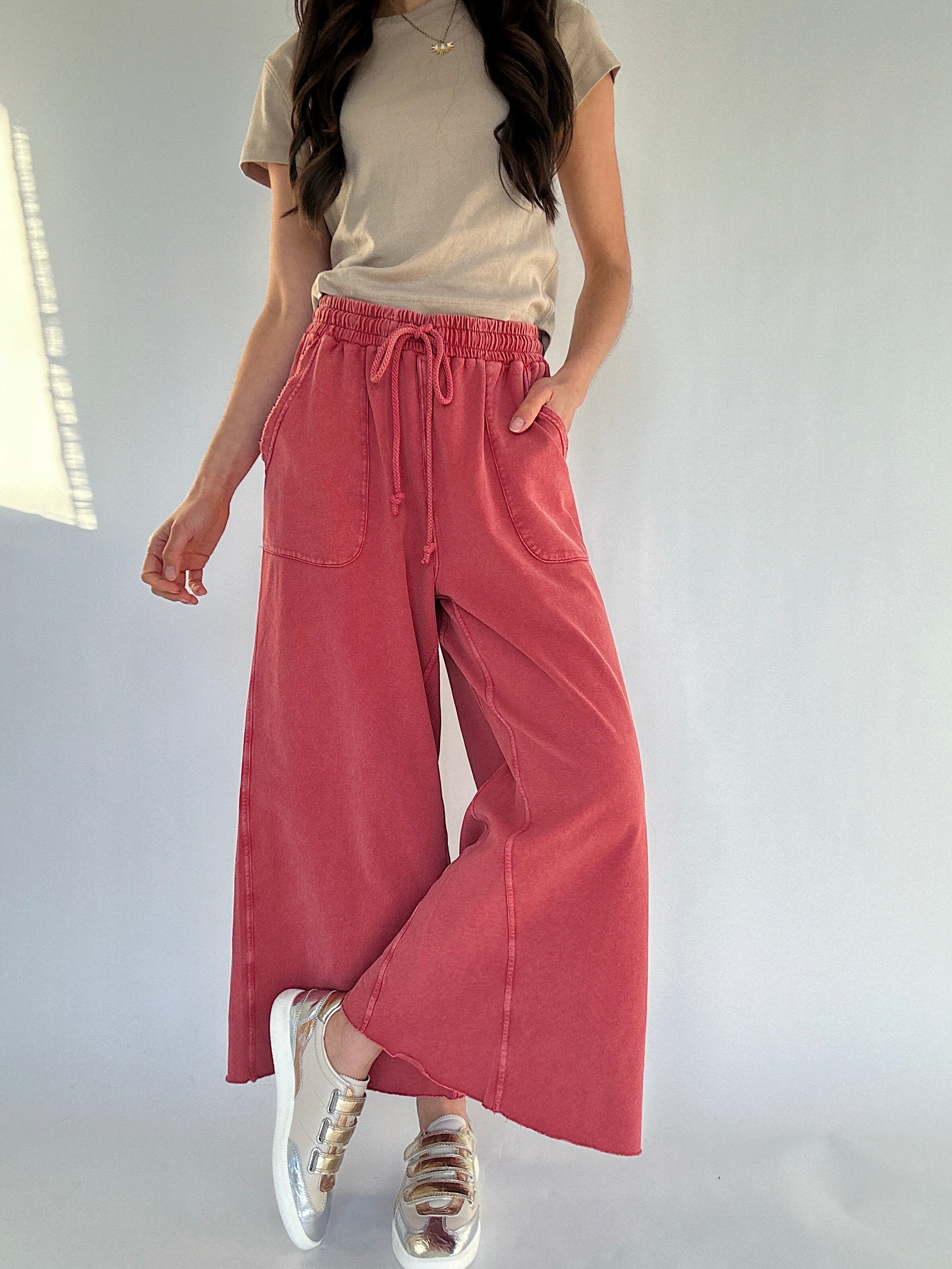 Person wearing a beige top and red wide-leg sweatpants on a white background