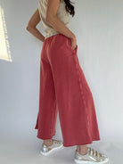 Person wearing red wide-leg sweatpants and silver sneakers on a white background showing backside