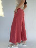 Person wearing red wide-leg sweatpants and silver sneakers on a plain background showing side pockets